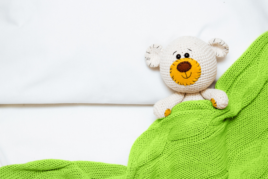 small-knitted-amigurumi-baby-toy-bear-is-covered-with-green-blanket.jpg